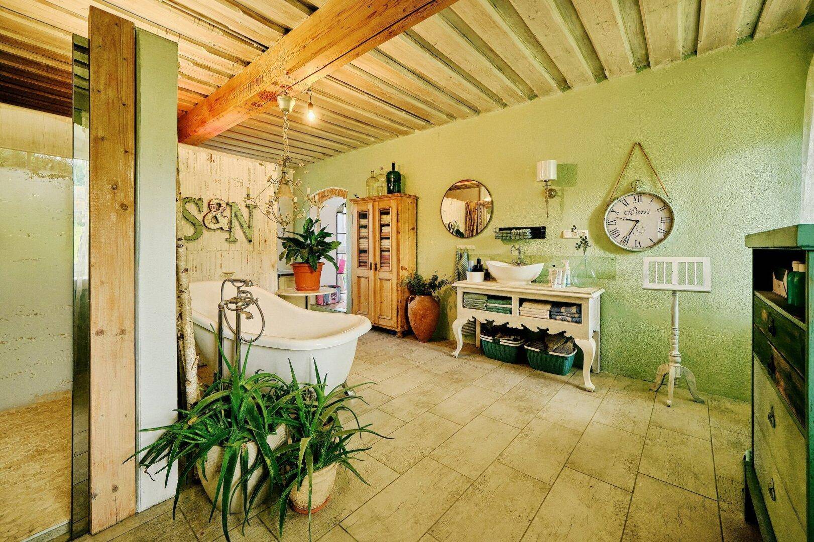 Geräumiges Badezimmer mit freistehender Badewanne, Doppelwaschbecken und grünen Wänden.