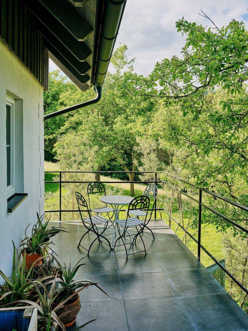 Kleiner Balkon mit schmiedeeisernen Möbeln und weitem Blick auf die grüne Landschaft.