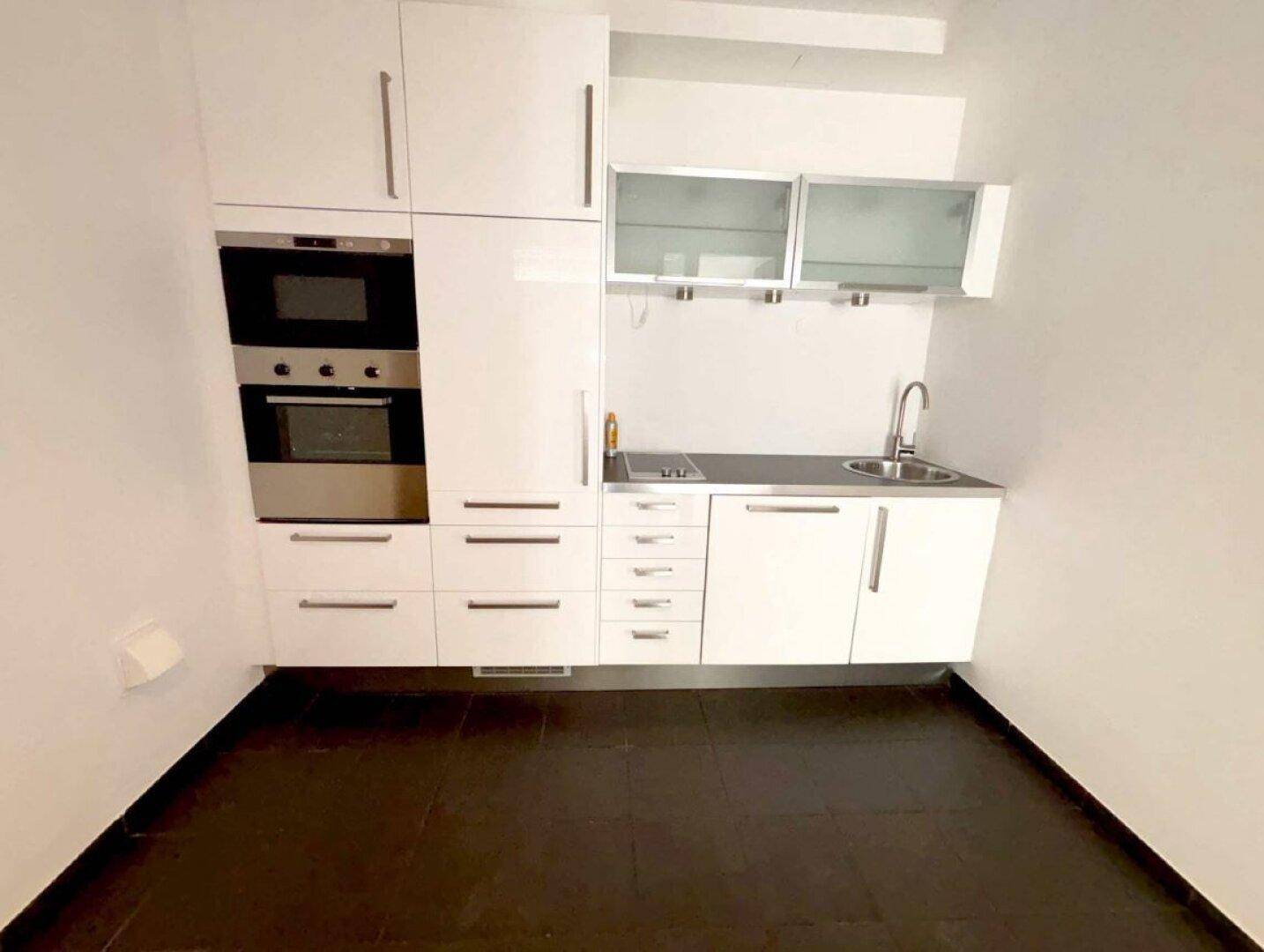 Detailansicht einer kompakten weißen Küchenzeile mit integriertem Backofen und Mikrowelle sowie Spüle.