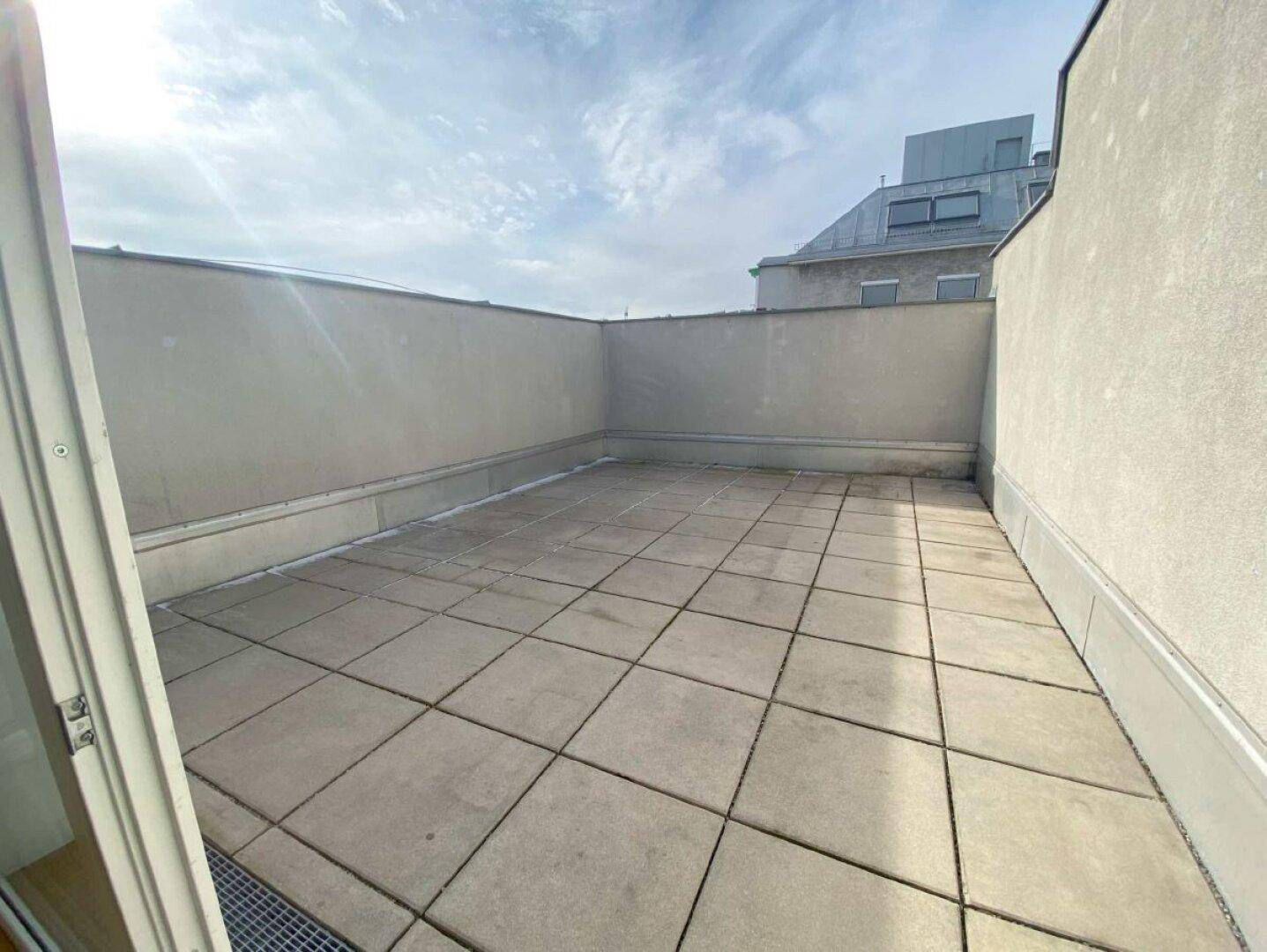 Geräumige Dachterrasse mit Fliesenboden und hohen Mauern, die Privatsphäre bieten.