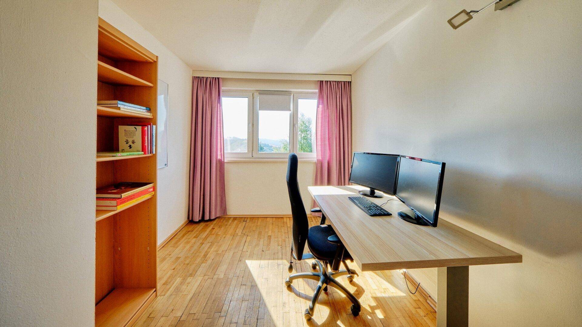 Ruhiges Schlafzimmer mit Holzboden, Schreibtisch und Bücherregal, ideal als Arbeitszimmer.