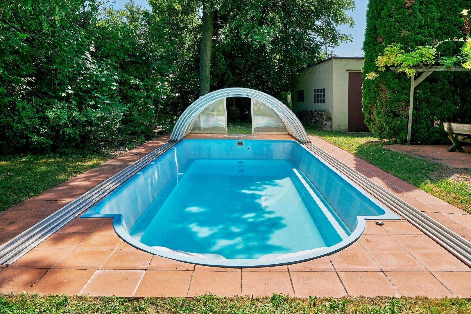 Großzügiger Poolbereich im Garten mit Terracotta-Fliesen und praktischer Überdachung für Badespaß.