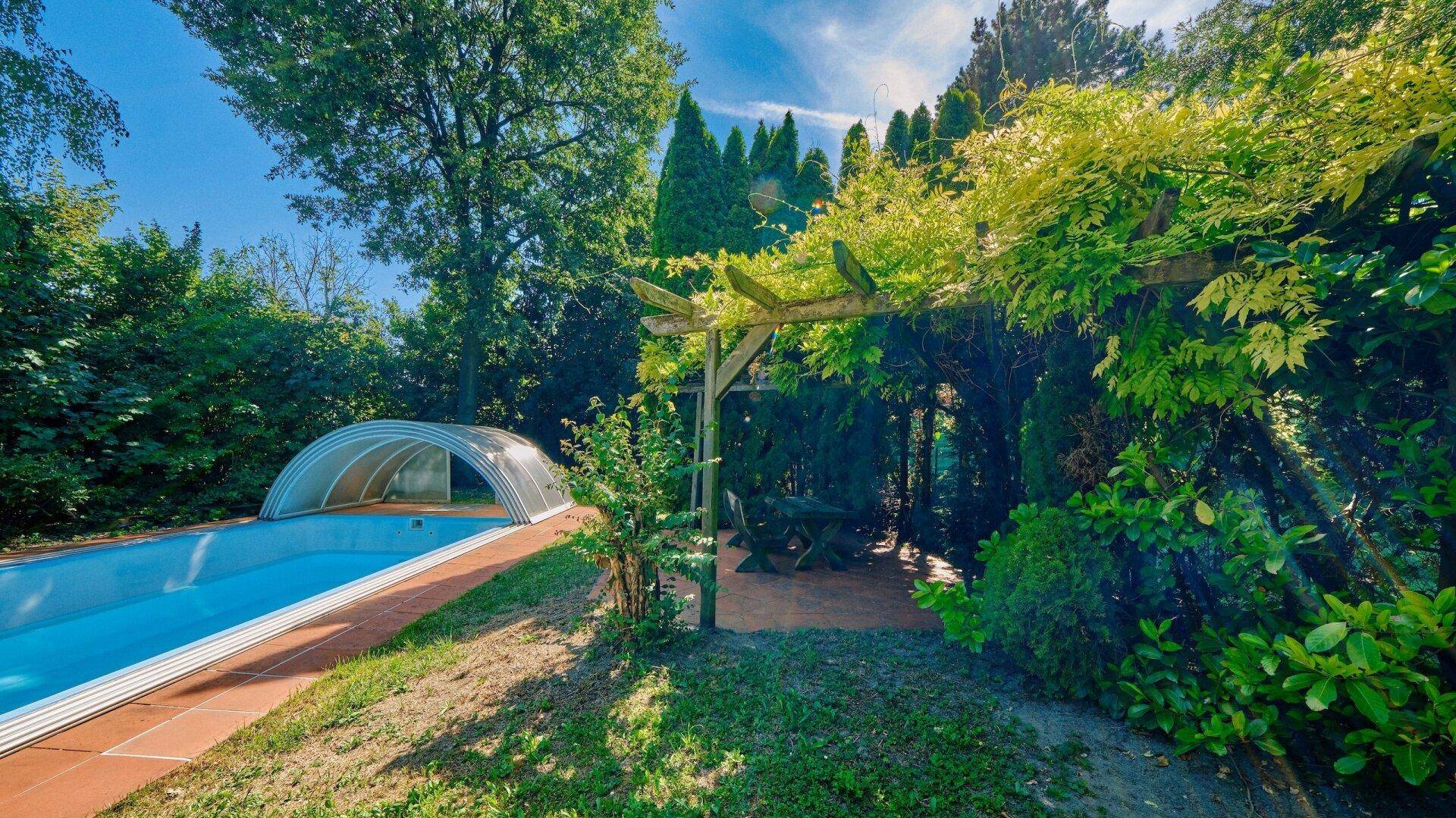 Idyllischer Gartenbereich mit Pergola und einem einladenden Pool für entspannte Sommertage.