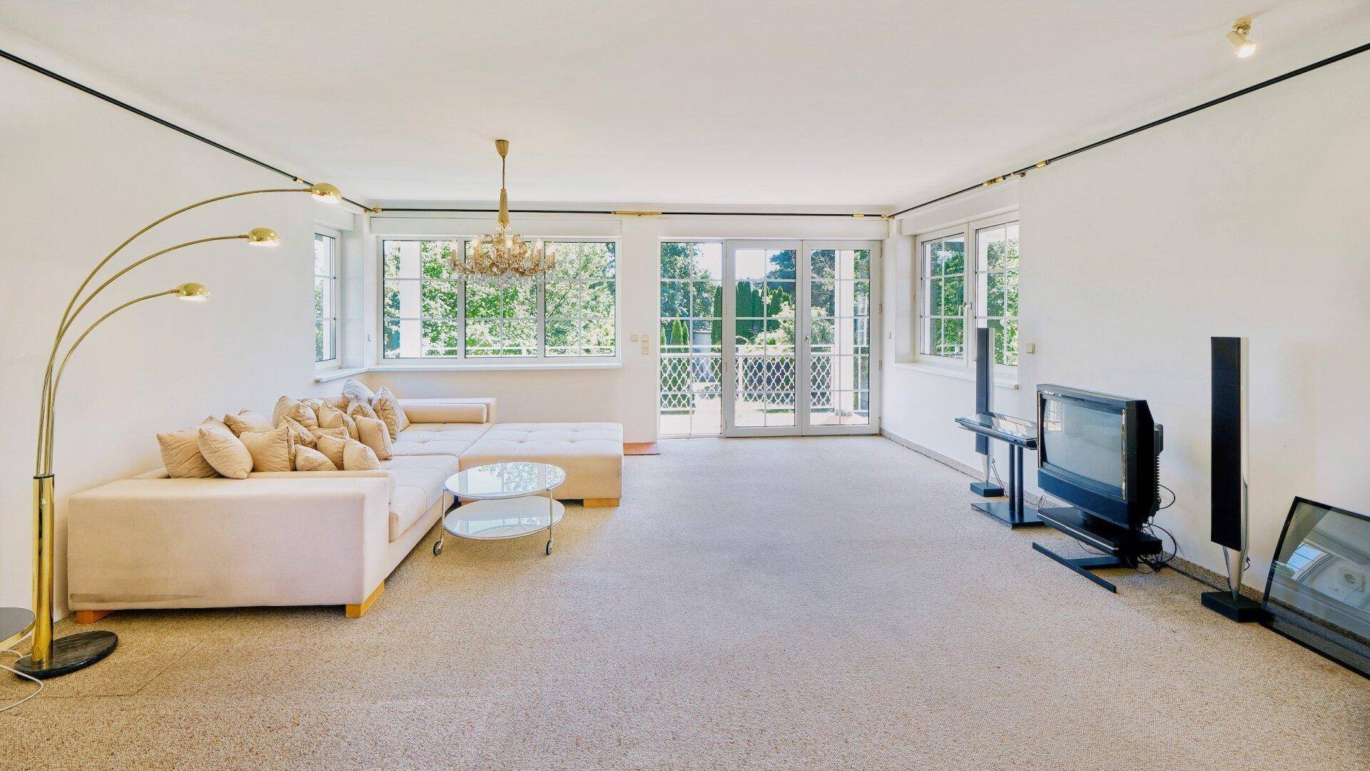 Helles Wohnzimmer mit Teppichboden, großem Sofa und direktem Zugang zum Balkon.