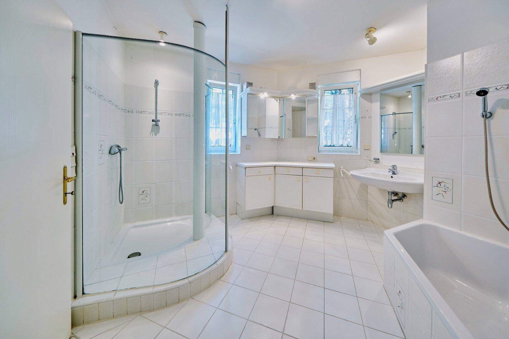 Geräumiges Badezimmer mit Duschkabine, Badewanne, Doppelwaschbecken und hellen Fliesen.