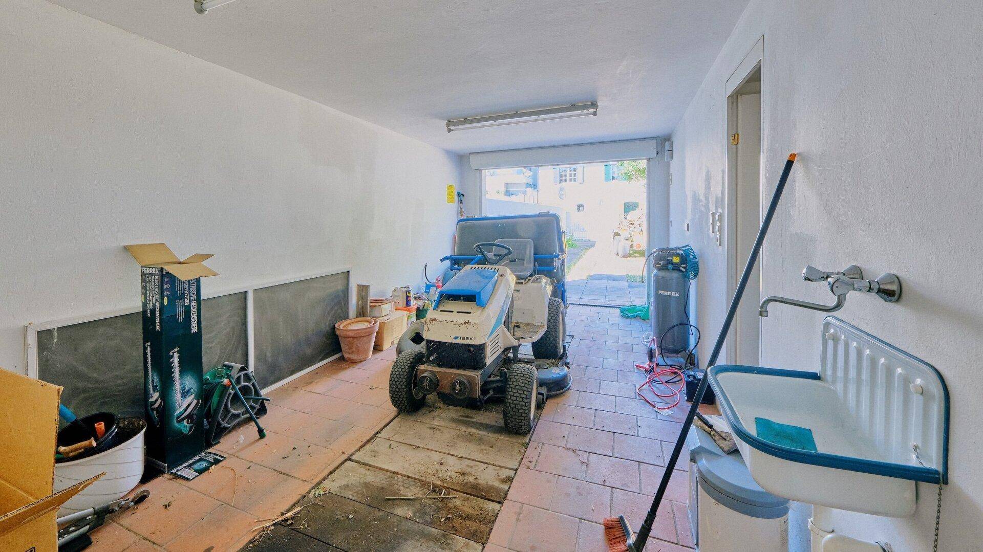 Geräumige Garage mit Werkstattbereich, Waschbecken und Zugang zum Außenbereich.