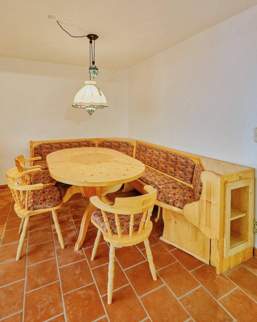 Traditionelle Essecke mit Holztisch, Eckbank und Stühlen, beleuchtet von einer Hängelampe.