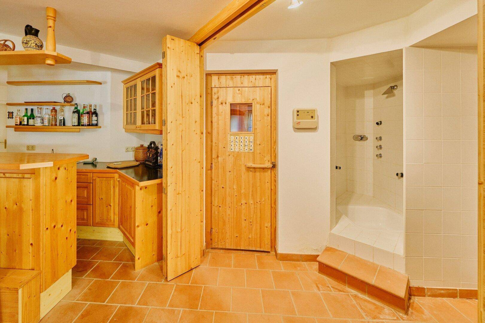 Wellnessbereich mit Holzelementen, Dusche und Zugang zur Sauna.