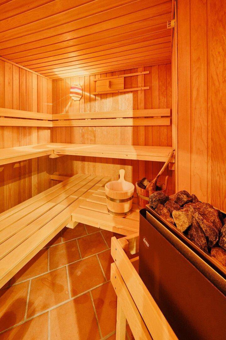 Gemütliche Holzsauna mit mehreren Bänken und traditionellem Saunaofen.