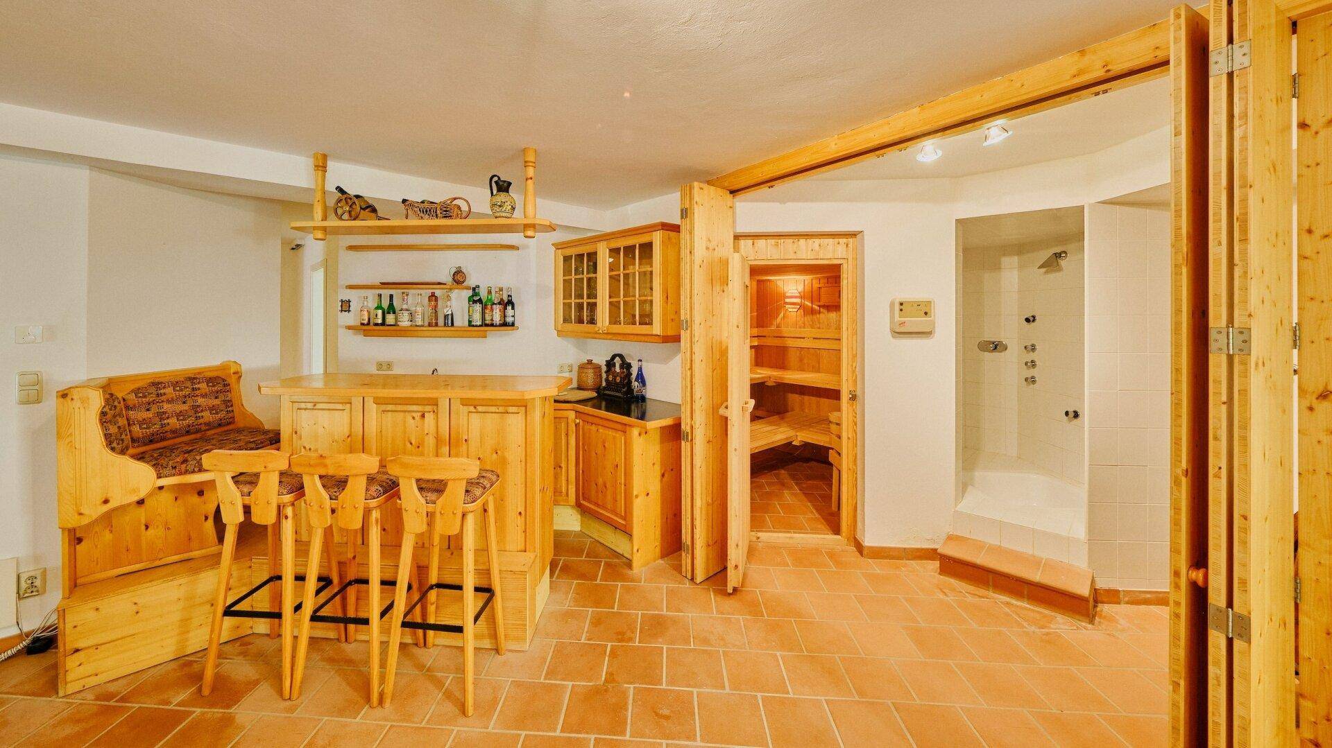 Geräumiger Wellnessbereich mit Barbereich, Sauna und Dusche, alles in Holz gehalten.
