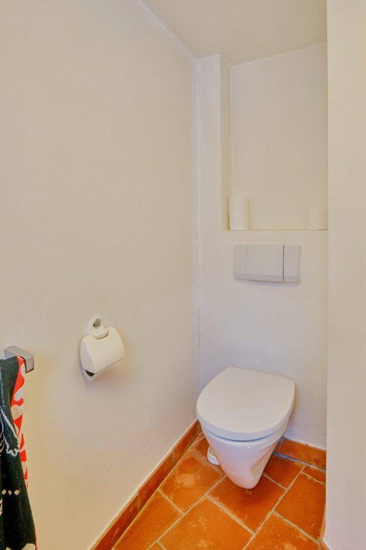 Kleines Gäste-WC mit Terrakottafliesen und wandhängender Toilette.