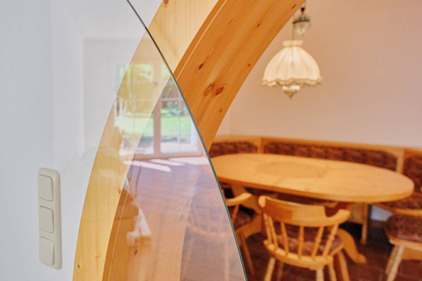 Detailansicht des runden Durchgangs mit Glasschiebetür und Blick auf die Essecke.