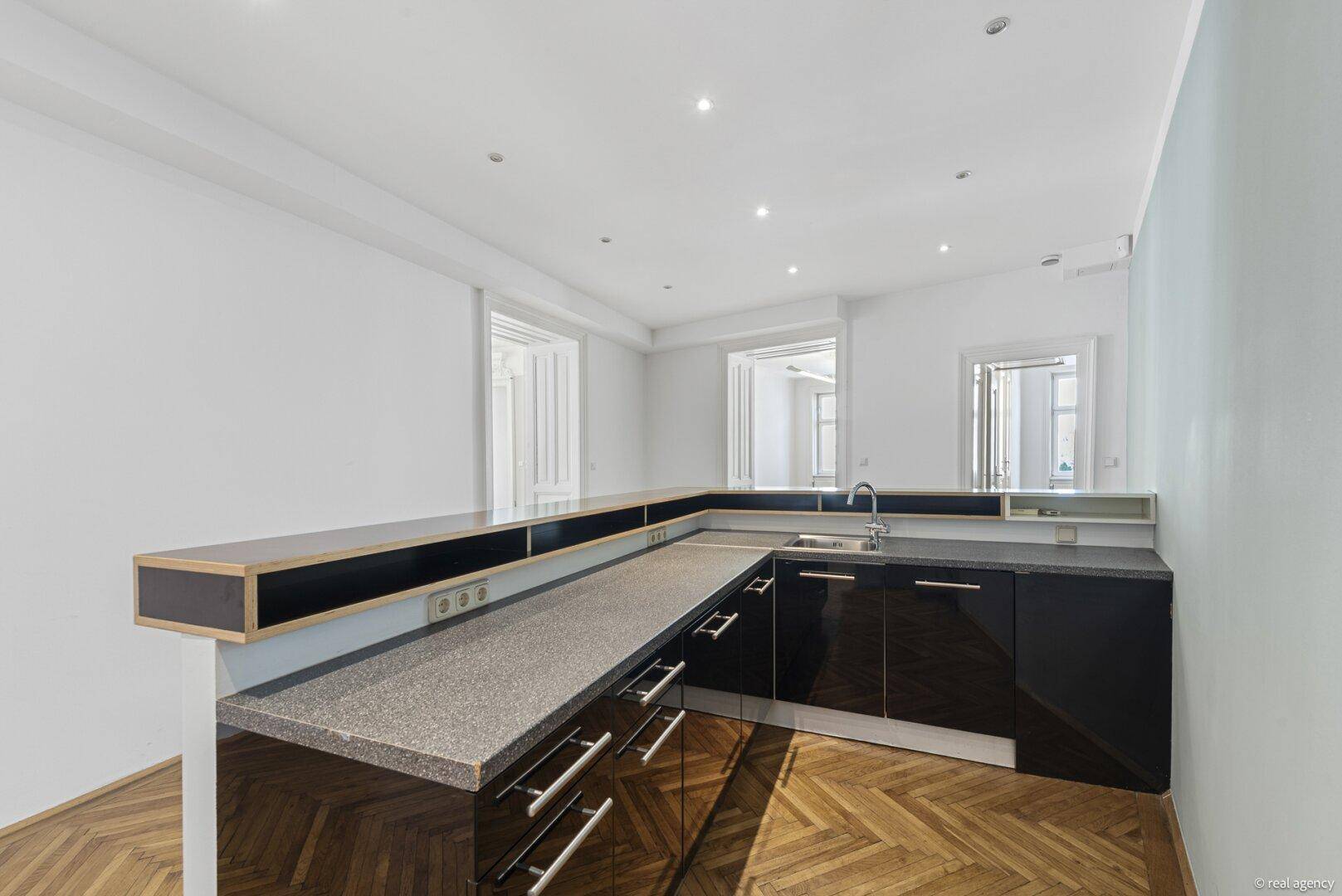 Moderne Küchenzeile mit dunklen Schränken, Granitarbeitsplatte und integriertem Spülbecken.