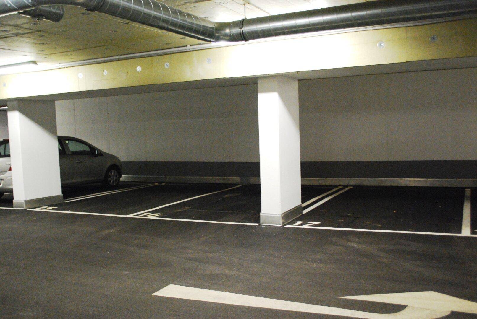 Weitere Ansicht der Tiefgarage mit mehreren leeren Stellplätzen, Säulen und klaren Markierungen.