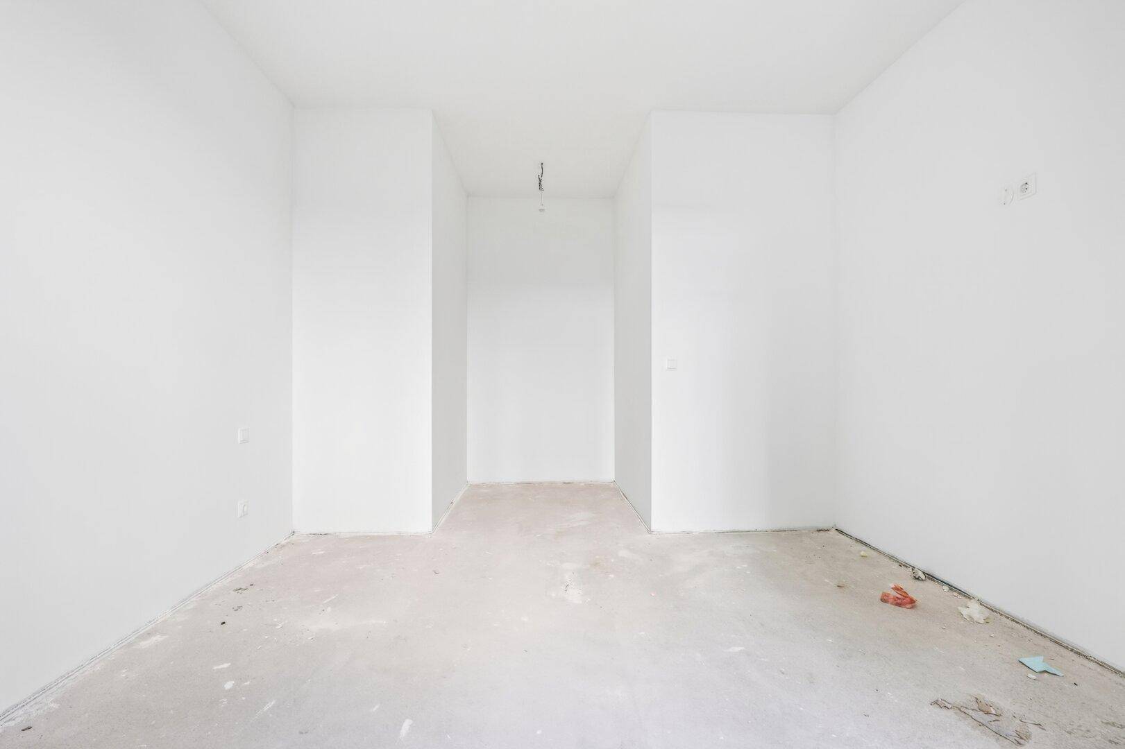 Schmaler, unfertiger Raum mit weißen Wänden, der auf den Innenausbau wartet.