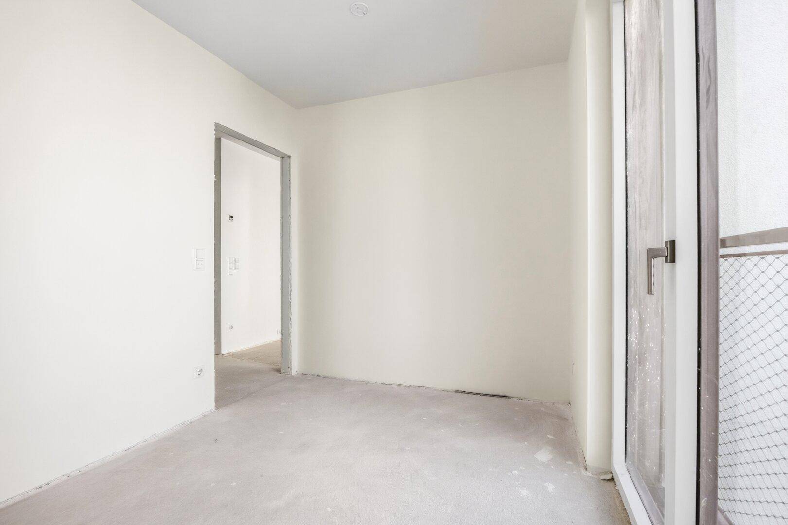 Leerer Raum mit weiß gestrichenen Wänden und einem Fenster mit französischem Balkon, bietet Potenzial für verschiedene Nutzungen.