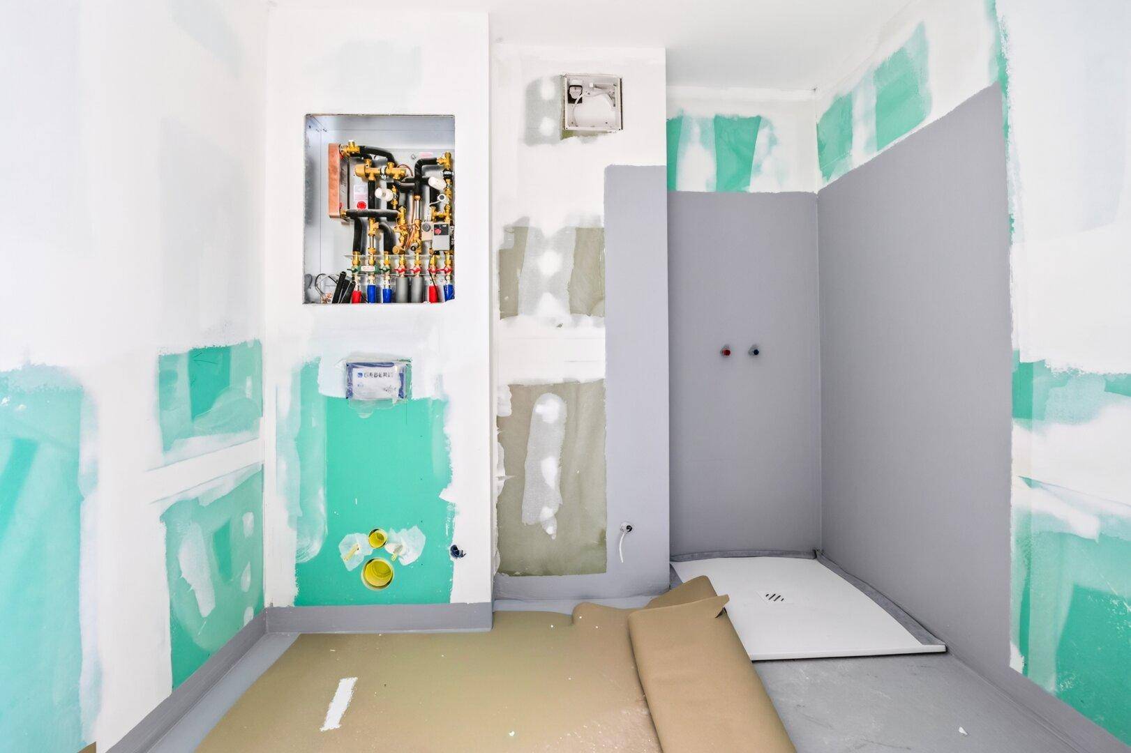 Badezimmer im Rohbau mit vorbereiteten Installationen und Duschbereich, bereit für die Endmontage.