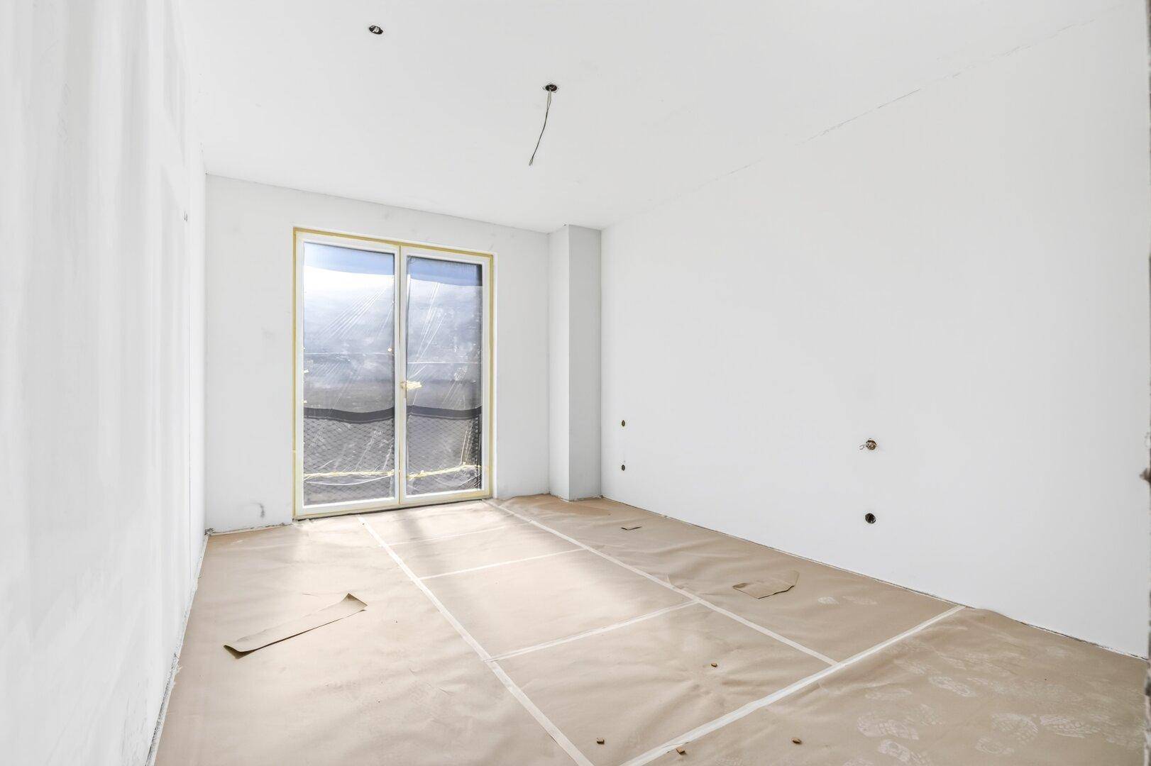 Heller Rohbau mit Schiebetür, die direkten Zugang zu einem Balkon oder einer Terrasse bietet.