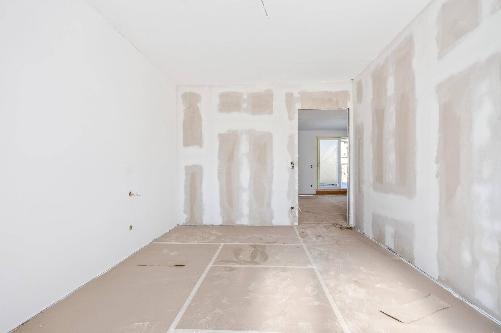 Heller Rohbau mit Durchgang zu einem weiteren Raum, bereit für den Innenausbau.