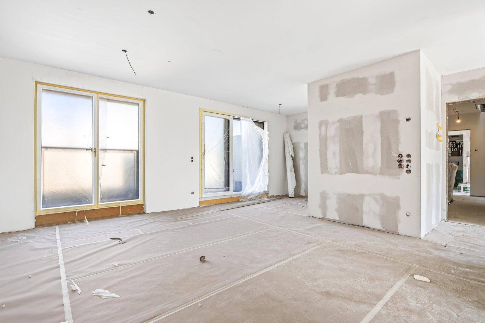 Geräumiger Rohbau mit viel Tageslicht und Zugang zu einem Außenbereich, ideal für offenes Wohnen.