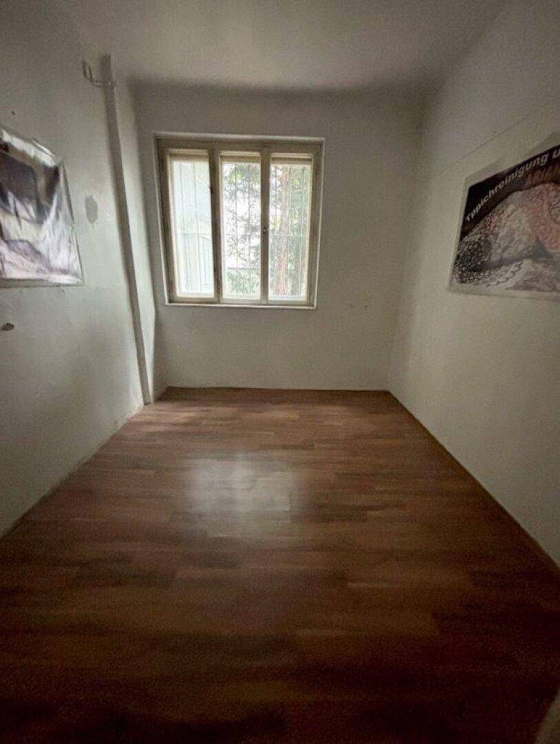 Leerer Raum mit Fenster und Laminatboden, bereit zur individuellen Gestaltung.
