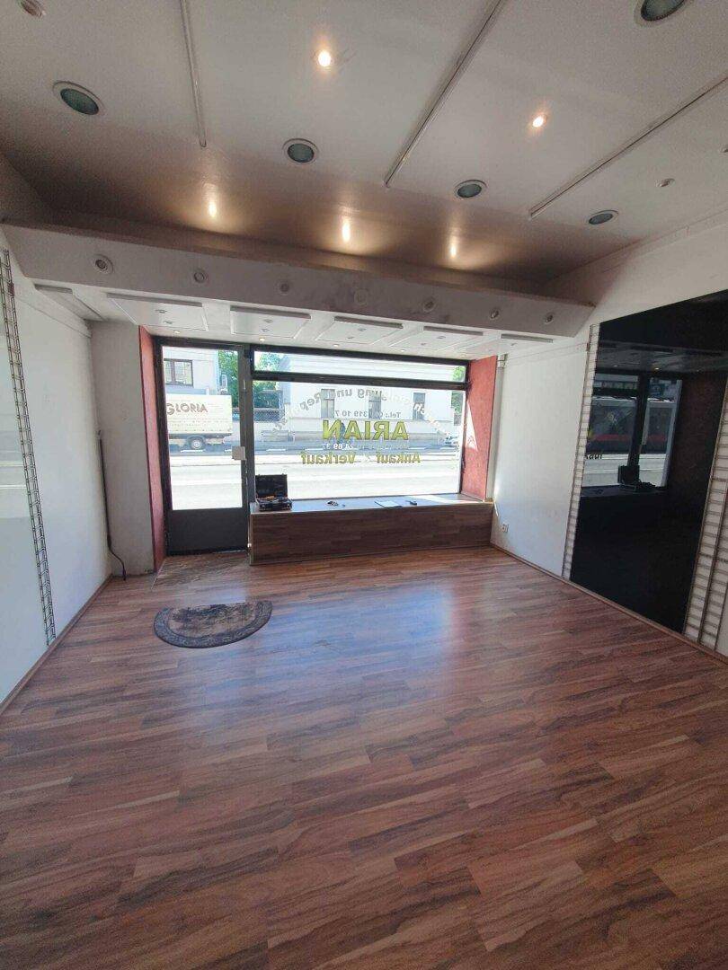 Heller Gewerberaum mit großem Schaufenster und Einbaustrahlern in der Decke.