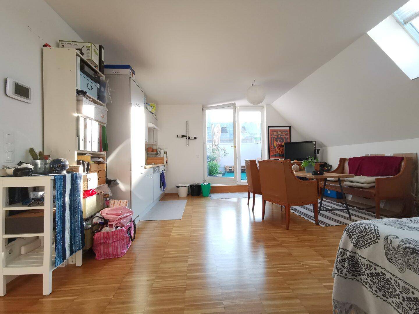 Gemütlicher Wohn- und Essbereich mit Holzboden, Dachschrägen und Zugang zur Terrasse.