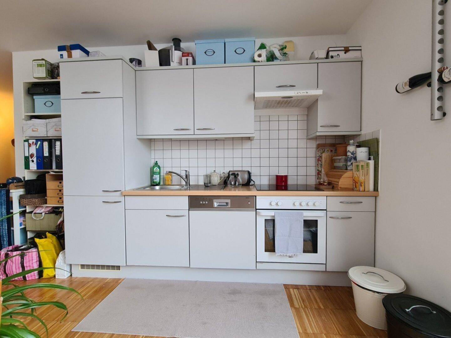 Funktionale Küche mit hellgrauen Schränken, Fliesenrückwand und integrierten Geräten.