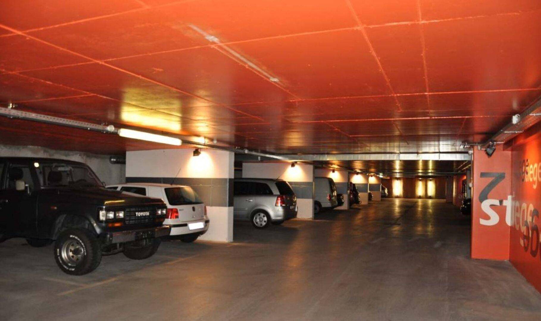 Helle und gut beleuchtete Tiefgarage mit Betonboden und markierten Parkbuchten.