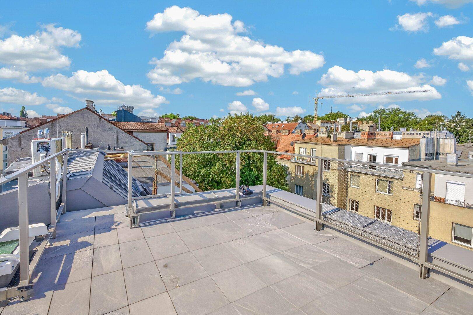Geräumige Dachterrasse mit modernen Fliesen und Blick auf die umliegende Stadtlandschaft.