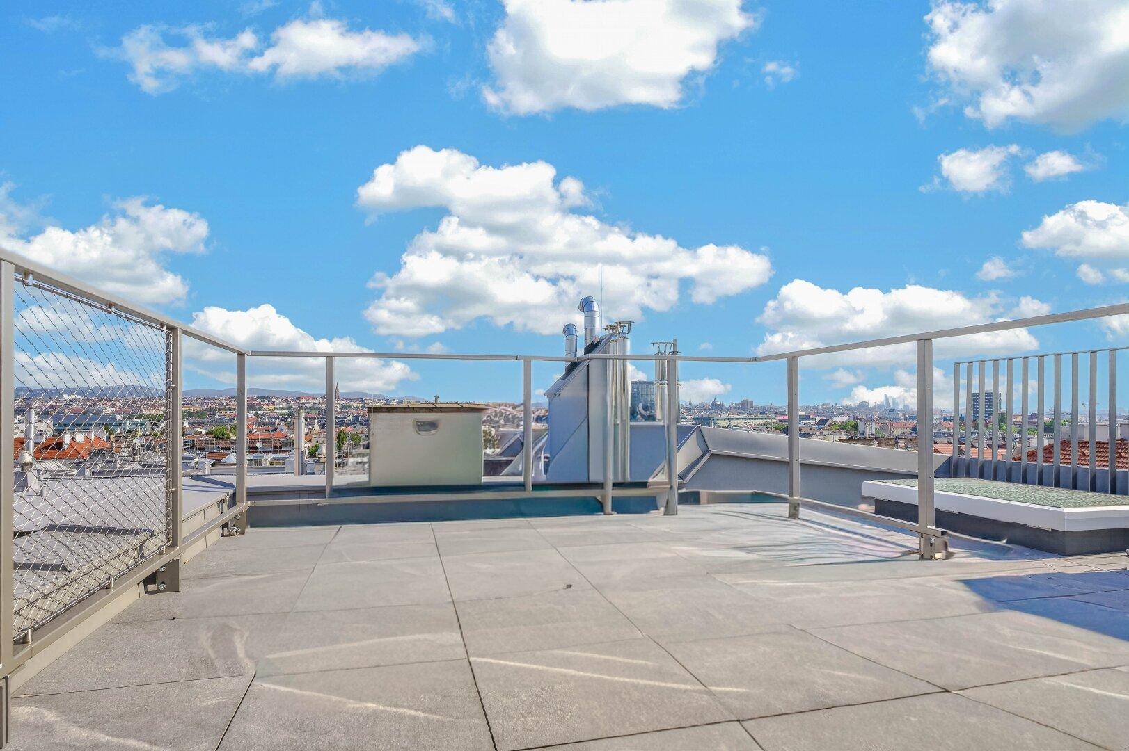 Weitläufige Dachterrasse mit moderner Metallbrüstung und Panoramablick über die Stadt.