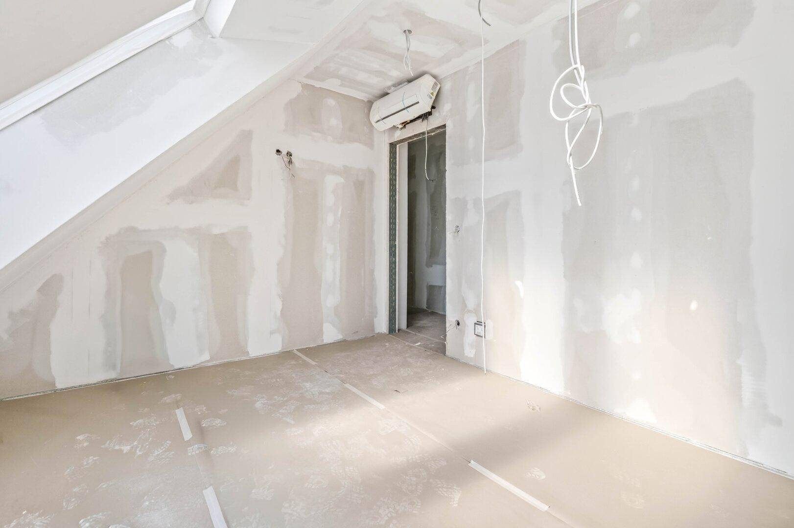 Rohbauzimmer mit Klimaanlage und Dachschräge, bereit für den Innenausbau und die Gestaltung.