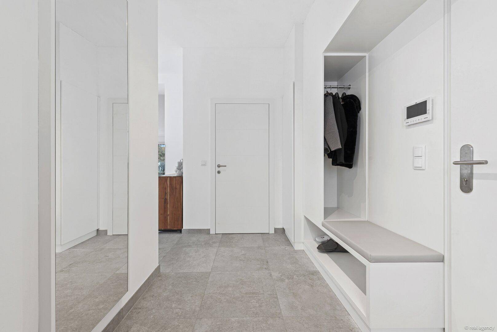 Eingangsbereich mit integrierter Garderobe, Sitzbank und großem Spiegel.