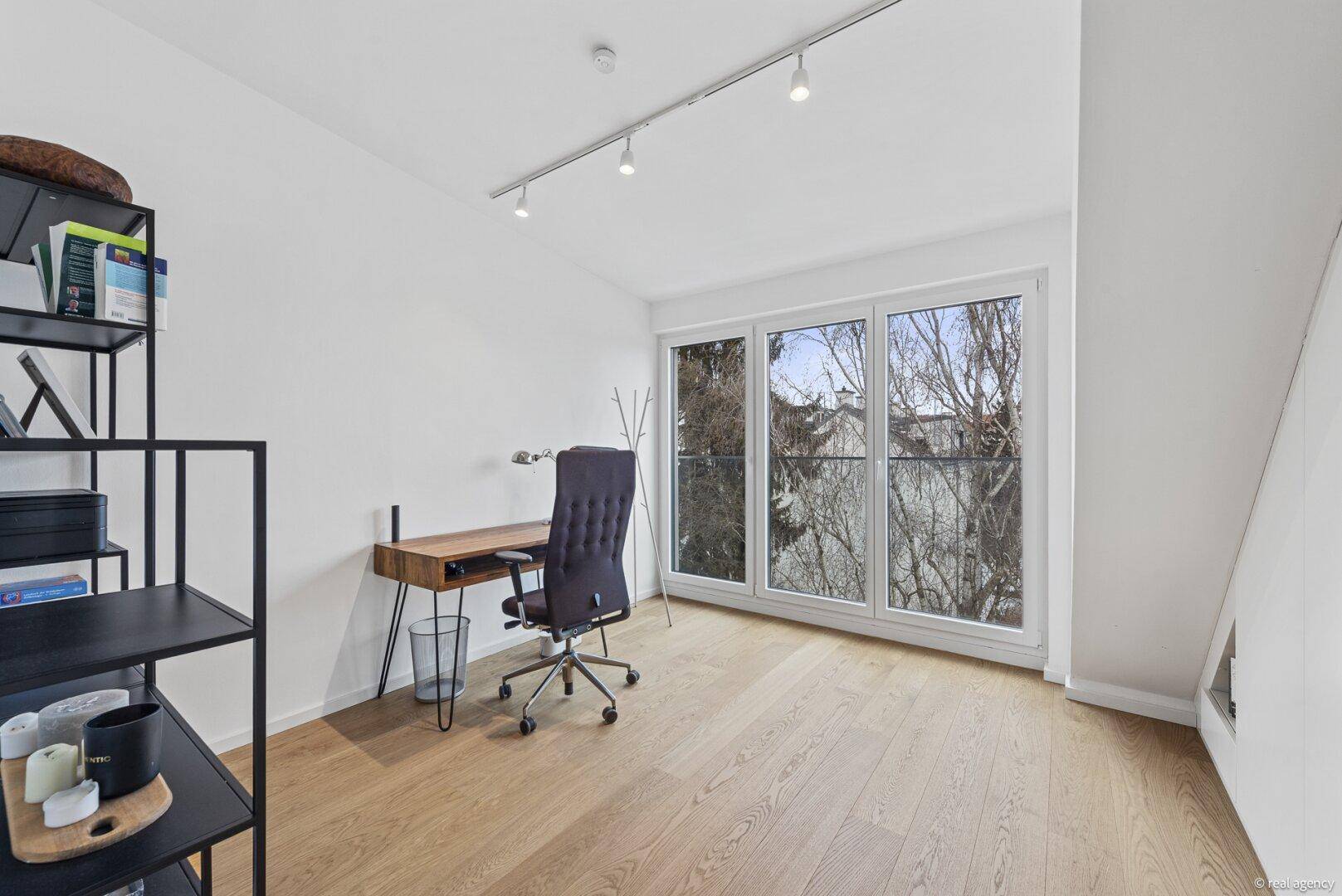 Helles Arbeitszimmer mit Holzboden, großem Fenster und Blick ins Grüne.