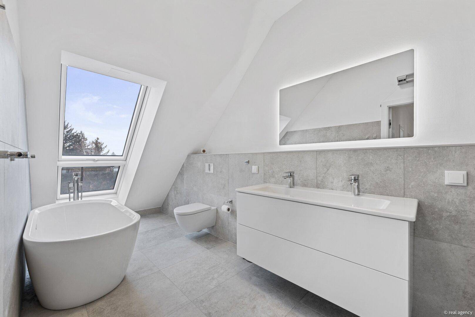 Modernes Badezimmer im Dachgeschoss mit freistehender Badewanne und Doppelwaschbecken.