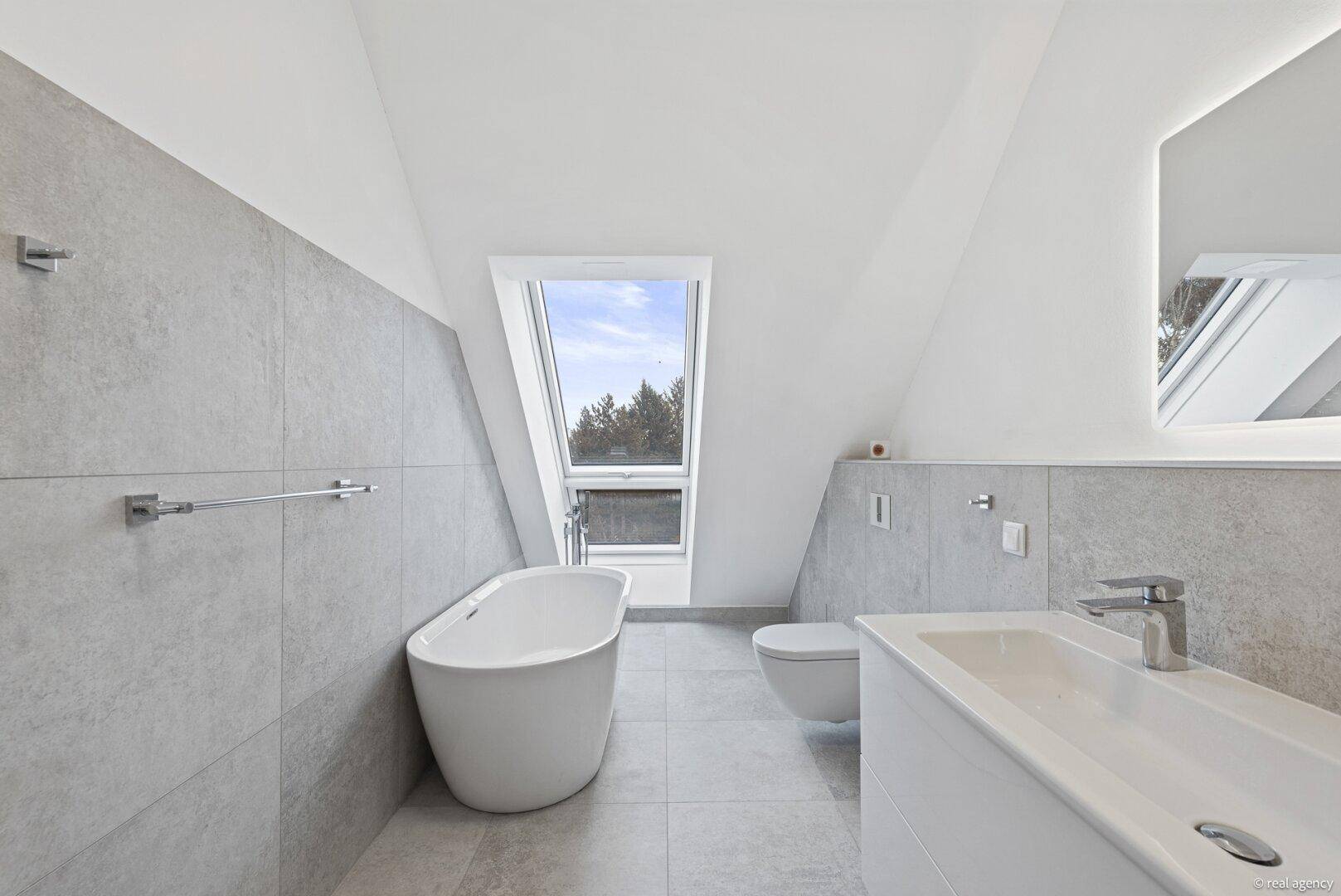 Elegantes Badezimmer mit freistehender Badewanne, Doppelwaschbecken und Dachfenster.