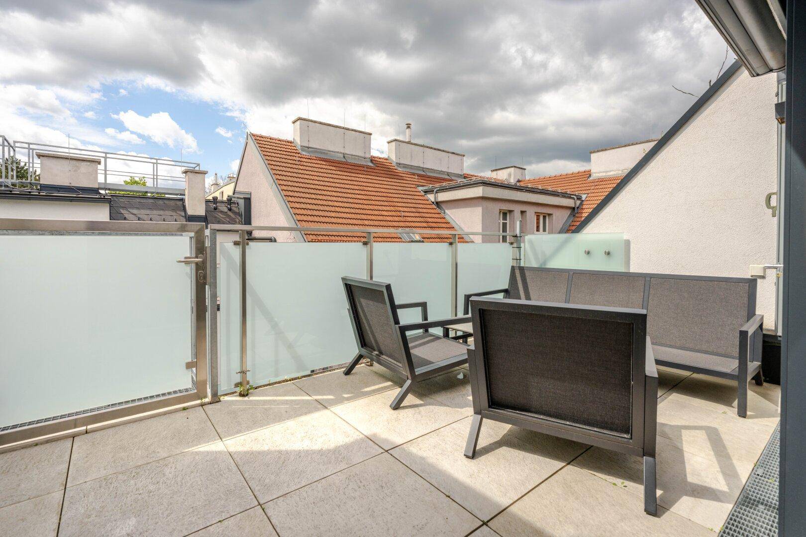 Geräumige Dachterrasse mit modernen Gartenmöbeln und Blick auf die umliegenden Dächer.