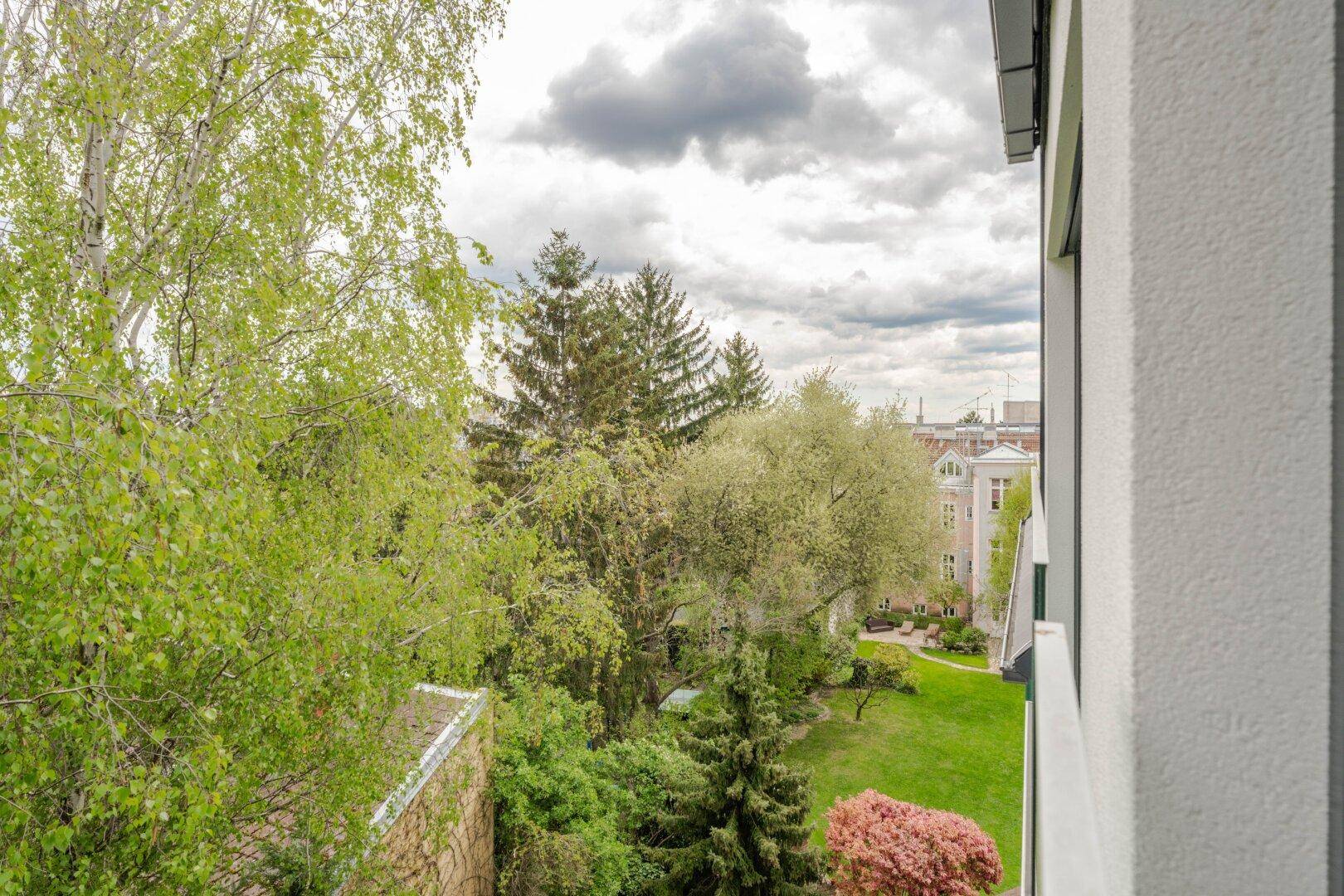 Weitläufiger Blick ins Grüne mit Bäumen und einem gepflegten Gartenbereich.