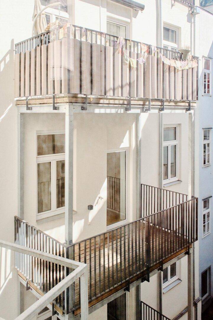 Mehrere Balkone mit modernen Metallgeländern an der Fassade eines Wohngebäudes, die zum Verweilen einladen.
