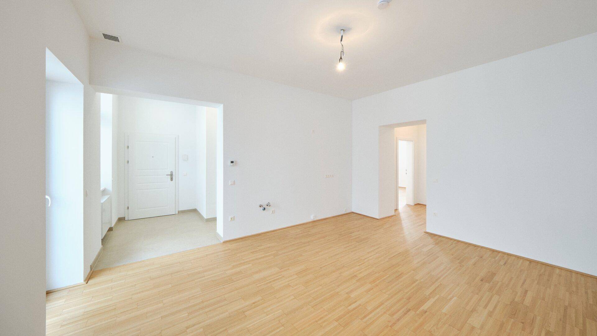 Geräumiges, leeres Zimmer mit Parkettboden und weiß gestrichenen Wänden, bereit zur Einrichtung.