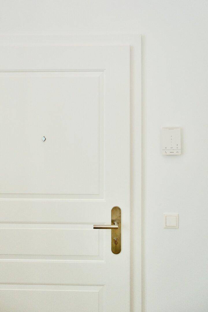 Detailansicht der weißen Eingangstür mit modernem Griff und Gegensprechanlage.