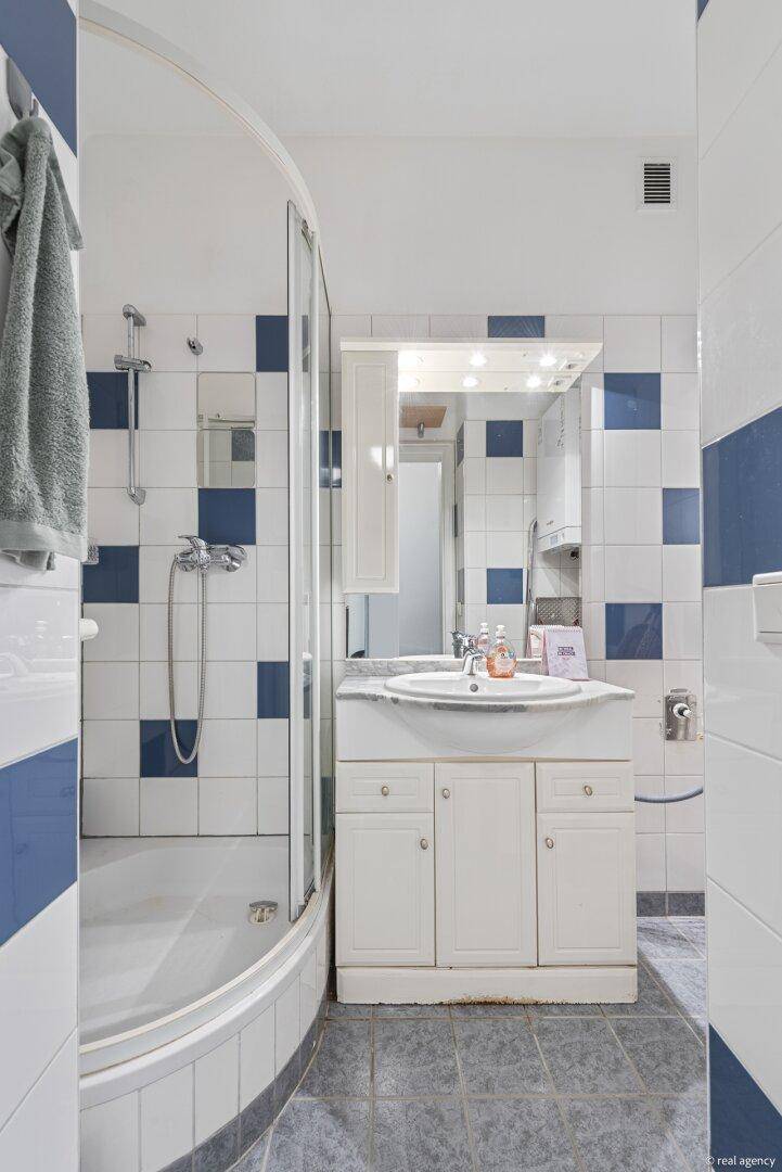 Badezimmer mit Duschkabine, Waschtisch und blau-weiß gefliesten Wänden und Boden.