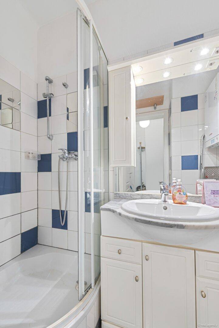 Badezimmer mit Duschkabine, Waschtisch und blau-weiß karierten Fliesen an den Wänden.