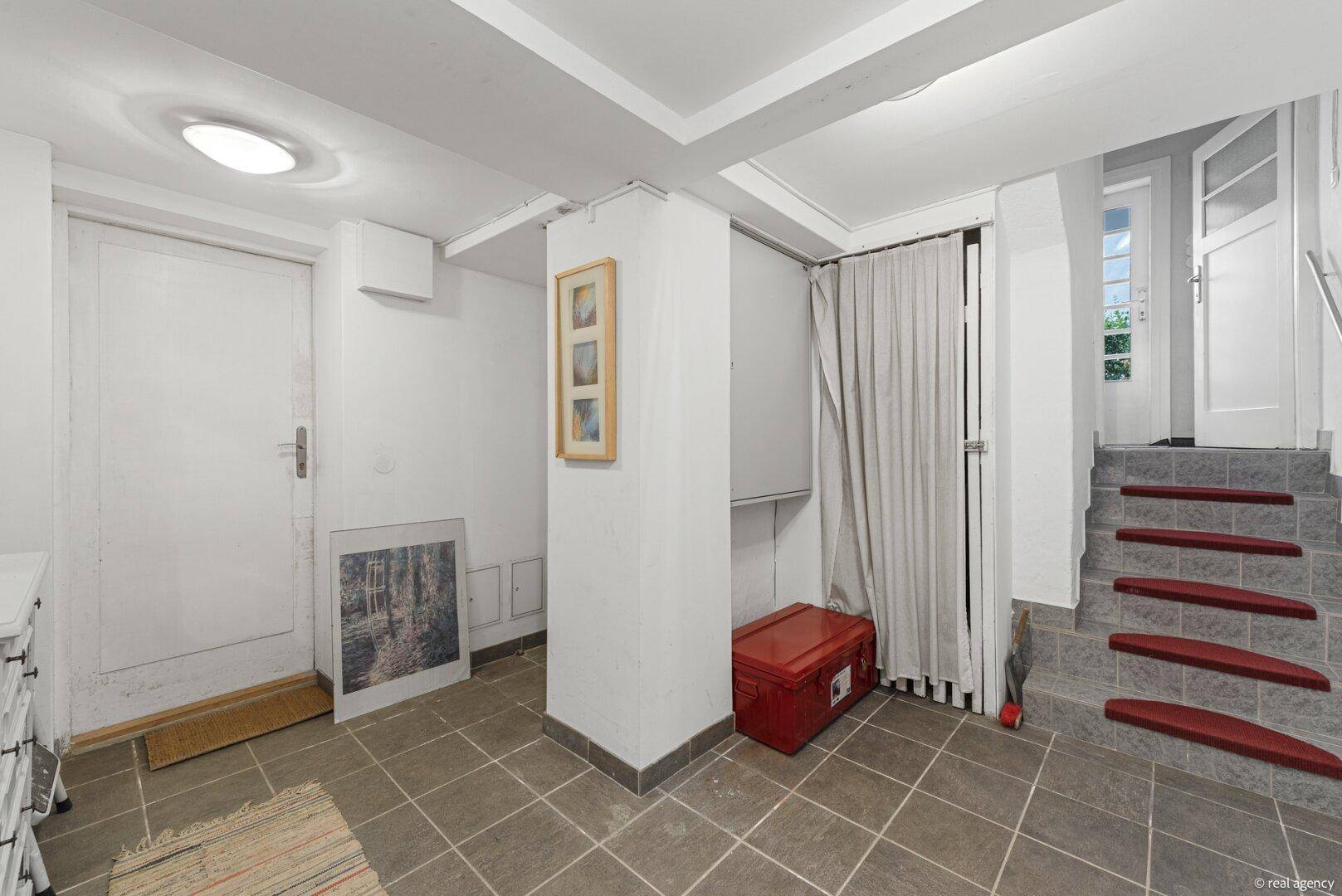 Kellerbereich mit gefliestem Boden, Treppe und Zugang zum Außenbereich des Hauses.