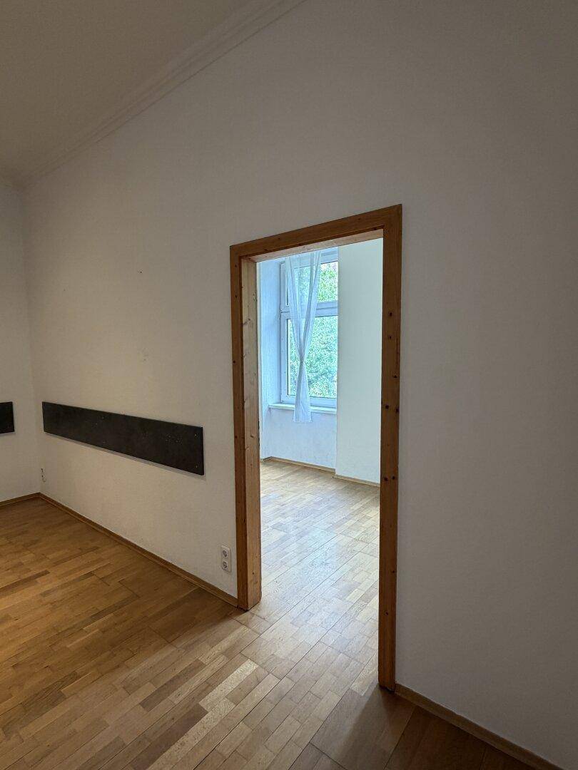 Heller Raum mit Parkettboden und Fenster, der viel Tageslicht hereinlässt.