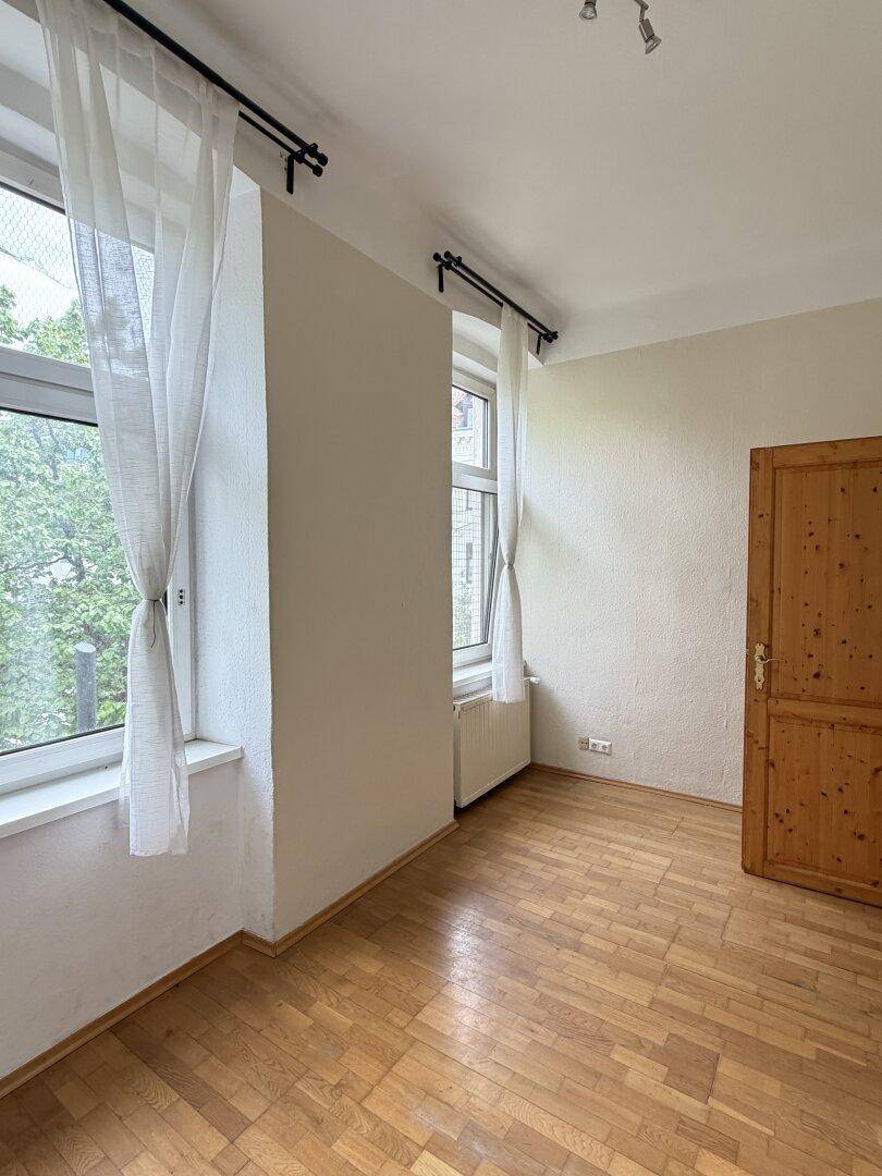 Schlafzimmer mit Parkettboden und Fenster mit Blick ins Grüne, ideal für Ruhe.
