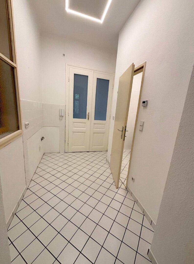 Geräumiger Flur mit weißen Fliesen und einer modernen Deckenbeleuchtung, die den Raum erhellt.