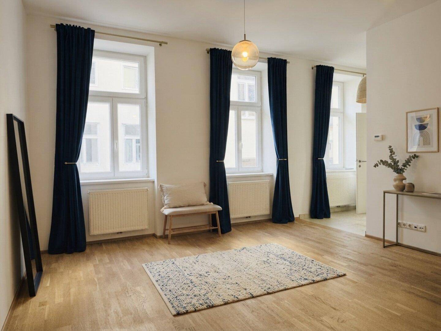 Geräumiges Wohnzimmer mit Holzboden, großen Fenstern und eleganten dunkelblauen Vorhängen.