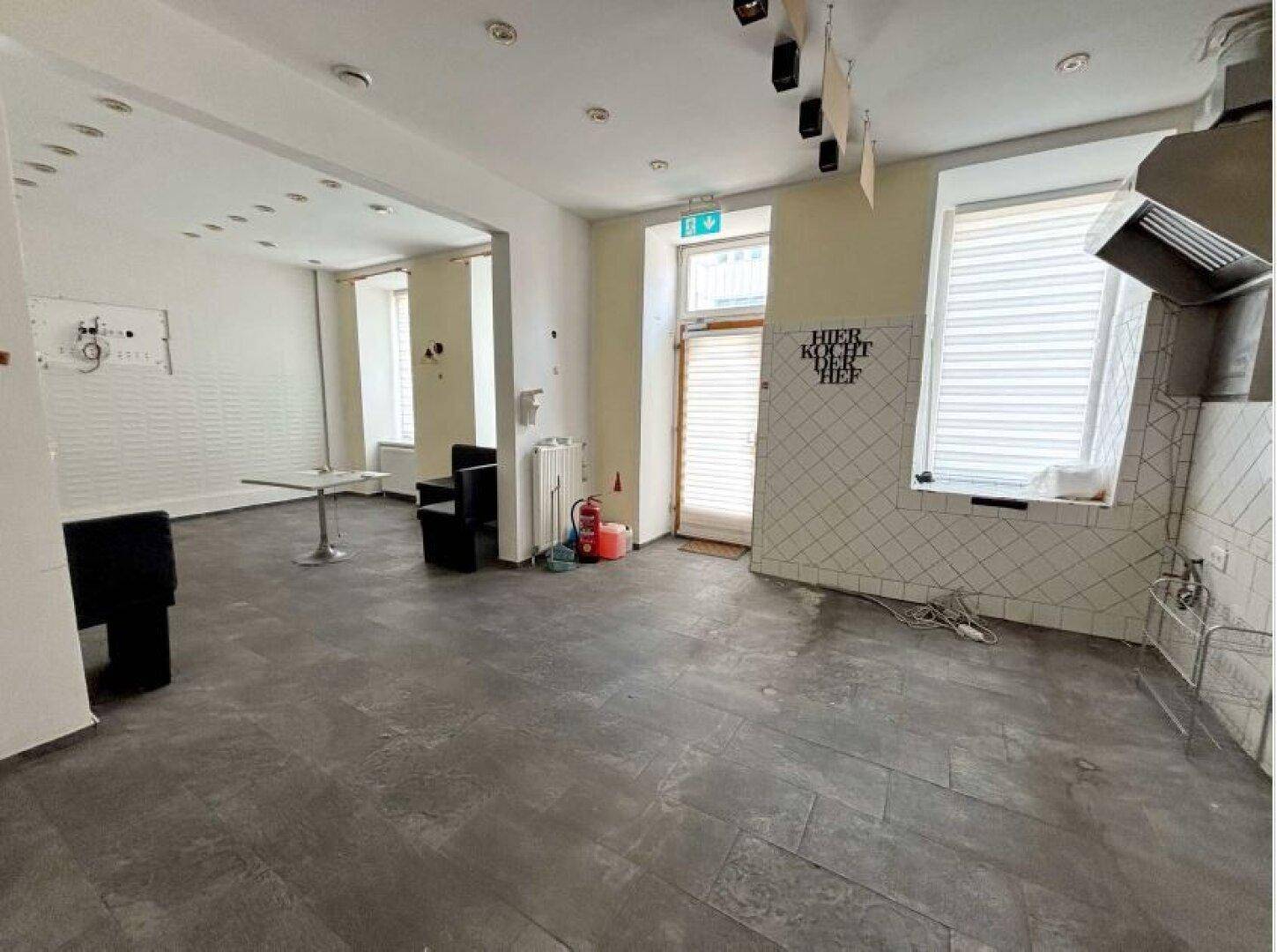 Großer Gewerberaum mit Fliesenboden, teilweise gefliesten Wänden und Tageslichteinfall.