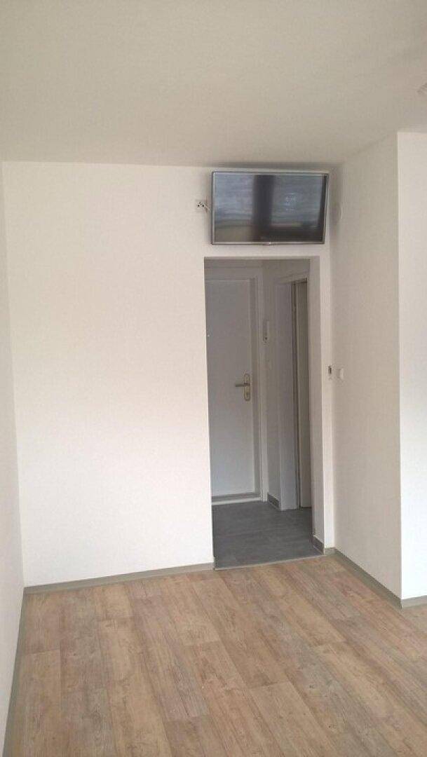Heller Flur mit Holzboden und Zugang zu weiteren Räumen, ausgestattet mit einer Wandhalterung.